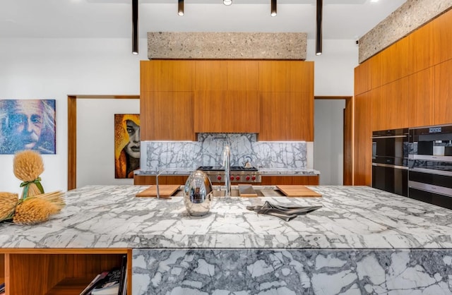 kitchen featuring black double oven, stainless steel gas cooktop, and decorative backsplash