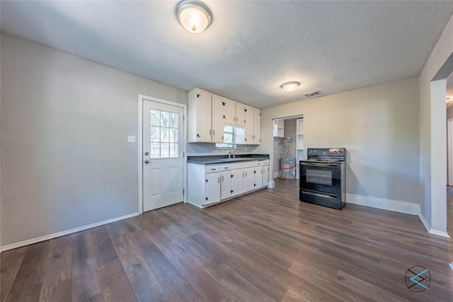 kitchen with black electric range oven, sink, dark wood-type flooring, white cabinetry, and a textured ceiling