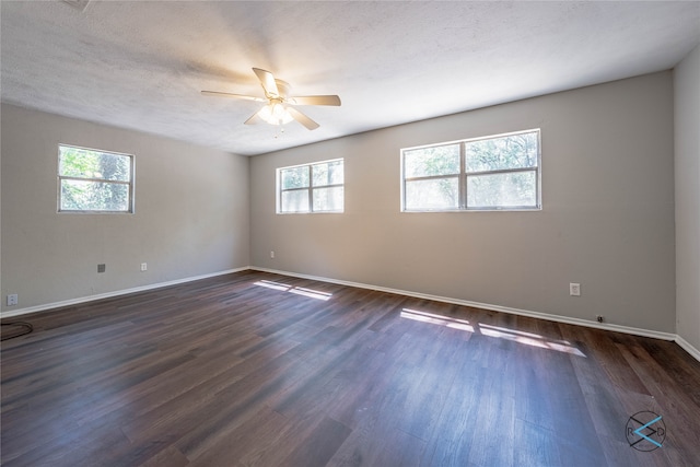 unfurnished room with a textured ceiling, a healthy amount of sunlight, ceiling fan, and dark wood-type flooring