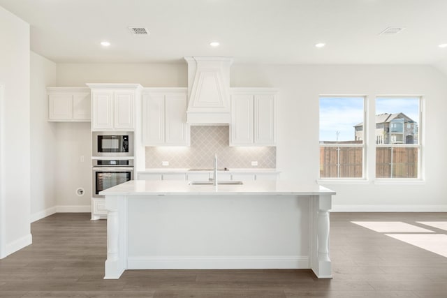 kitchen with sink, white cabinets, oven, a kitchen island with sink, and backsplash