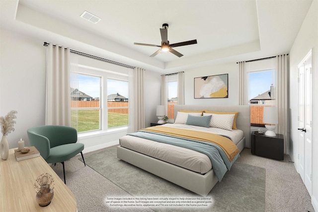 carpeted bedroom featuring ceiling fan and a tray ceiling