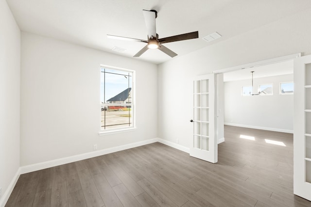 unfurnished room with hardwood / wood-style flooring, ceiling fan with notable chandelier, and french doors