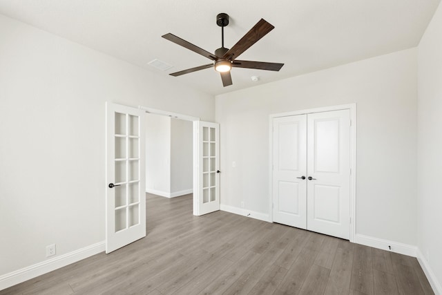 unfurnished bedroom with a closet, light hardwood / wood-style floors, french doors, and ceiling fan