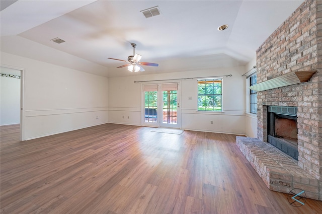 unfurnished living room featuring lofted ceiling, hardwood / wood-style floors, ceiling fan, and a brick fireplace