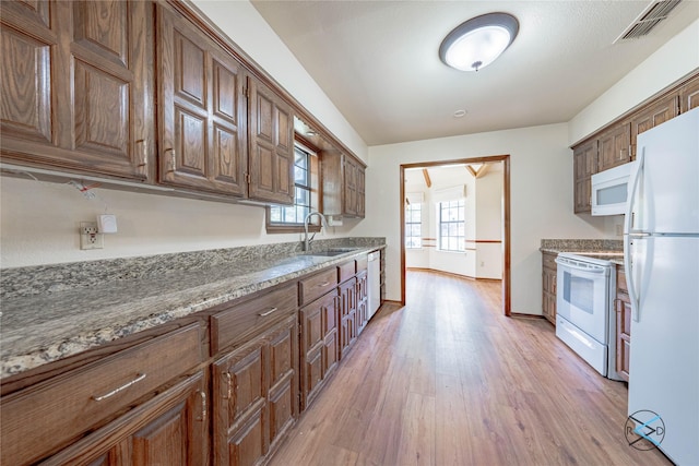 kitchen featuring light hardwood / wood-style floors, white appliances, light stone countertops, and sink