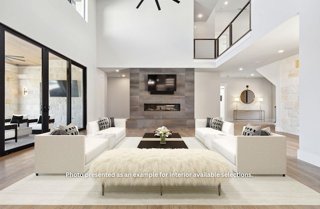 living room with light hardwood / wood-style floors, a tile fireplace, and a high ceiling