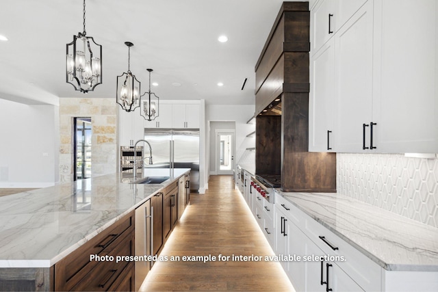 kitchen with light stone countertops, a spacious island, sink, pendant lighting, and white cabinets