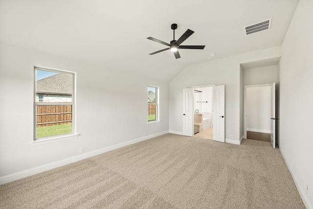 unfurnished bedroom with light carpet, lofted ceiling, ensuite bath, and ceiling fan