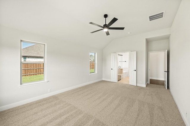 unfurnished bedroom with connected bathroom, visible vents, baseboards, lofted ceiling, and carpet