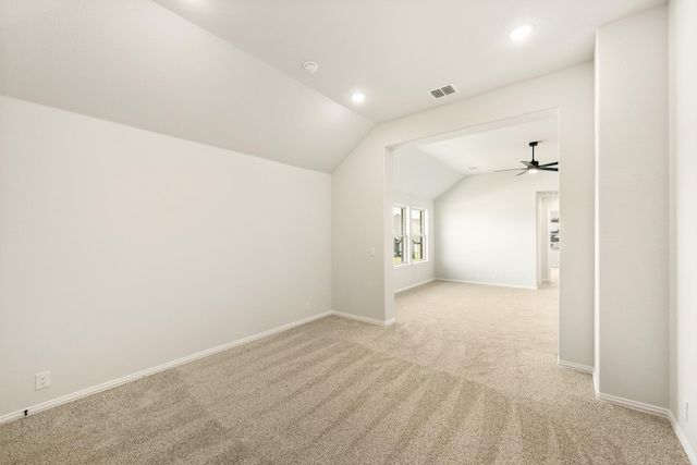 additional living space featuring light colored carpet, baseboards, visible vents, and vaulted ceiling