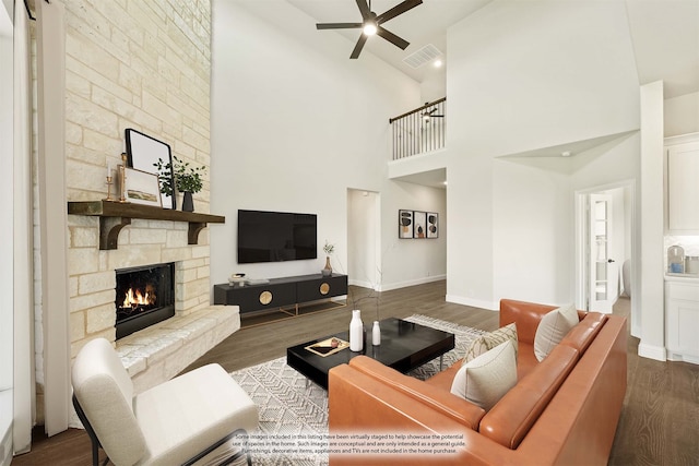 living room with dark wood-type flooring, ceiling fan, high vaulted ceiling, and a fireplace