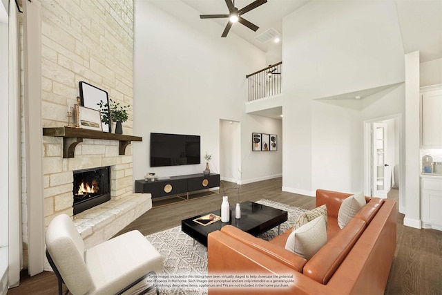 living area featuring visible vents, wood finished floors, a fireplace, ceiling fan, and high vaulted ceiling