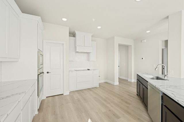 kitchen with light hardwood / wood-style floors, white cabinetry, light stone countertops, and sink