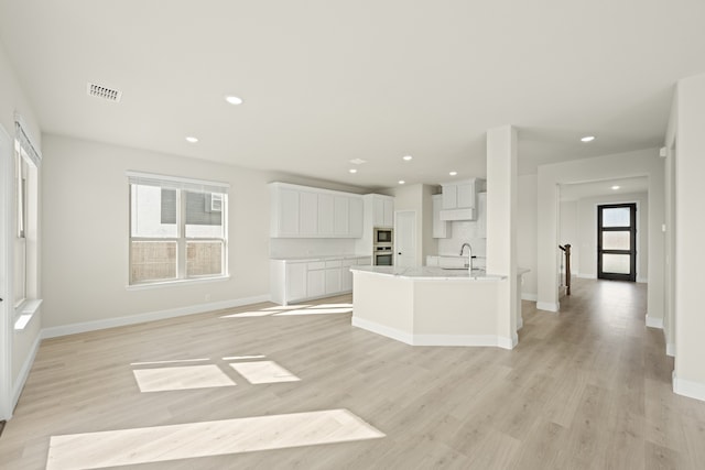 unfurnished living room featuring sink and light wood-type flooring