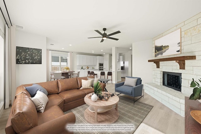living room featuring a fireplace, light wood-style flooring, a ceiling fan, recessed lighting, and visible vents