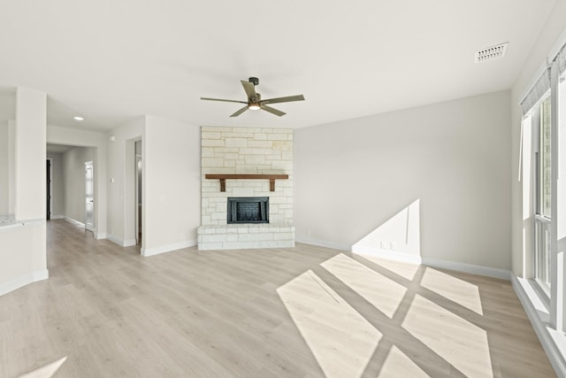 unfurnished living room featuring a ceiling fan, visible vents, a fireplace, baseboards, and light wood-style flooring