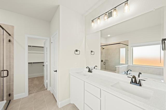 bathroom featuring a walk in closet, a sink, tile patterned floors, and a stall shower
