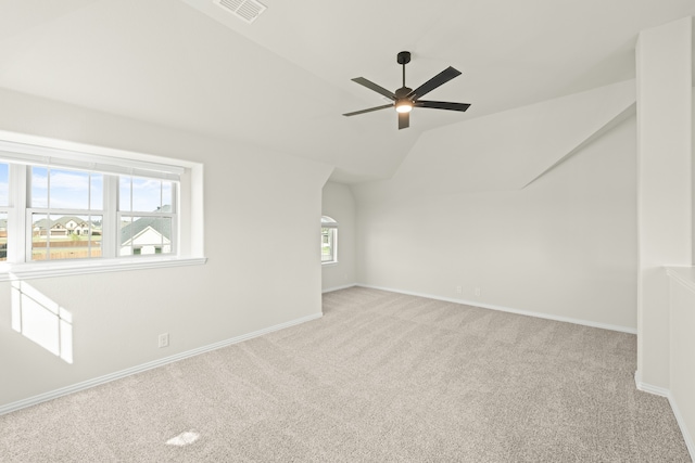 additional living space featuring lofted ceiling, ceiling fan, light colored carpet, and plenty of natural light