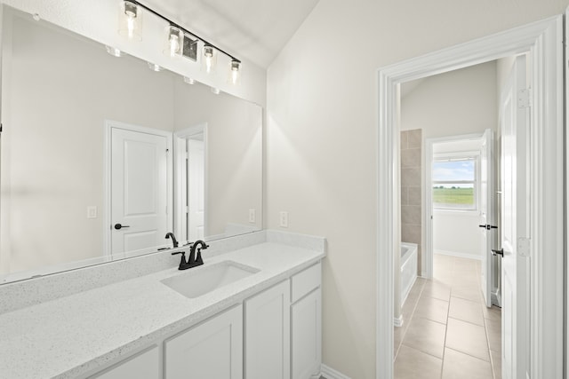 bathroom with vanity, a bathtub, lofted ceiling, and tile patterned floors