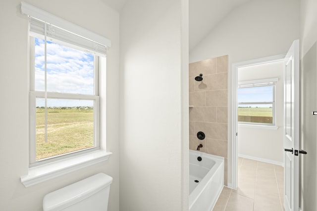 bathroom featuring toilet, tiled shower / bath, tile patterned floors, and vaulted ceiling