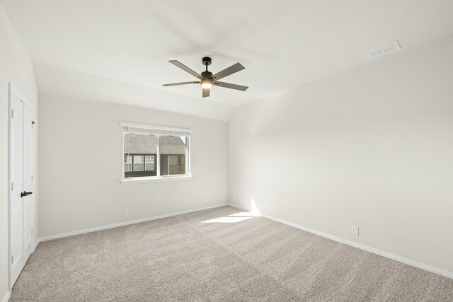 empty room featuring lofted ceiling, carpet floors, and ceiling fan