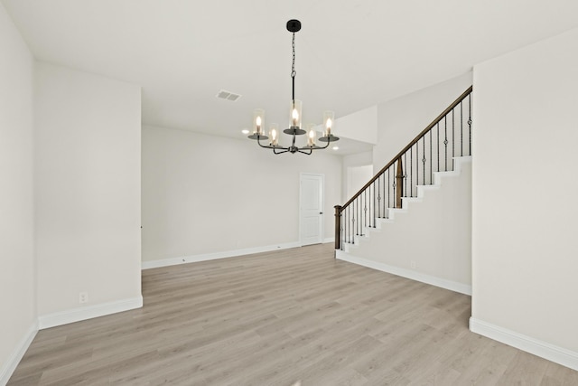 interior space with baseboards, light wood finished floors, stairs, and a chandelier