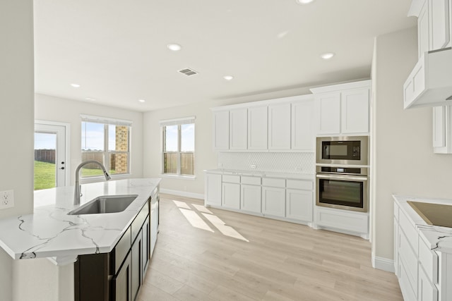 kitchen featuring white cabinets, sink, light wood-type flooring, and stainless steel oven