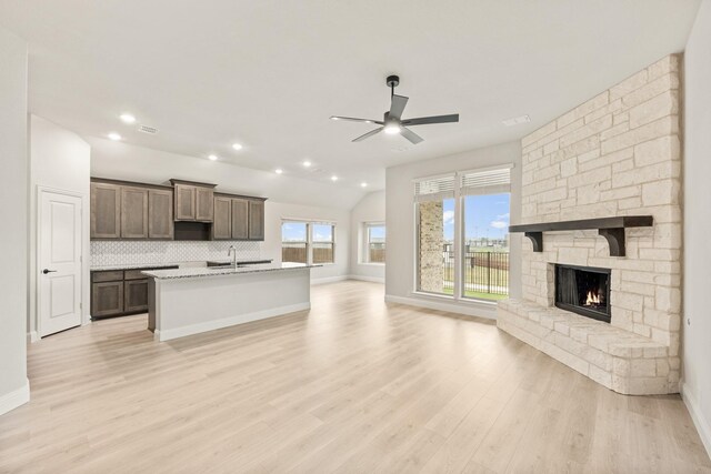 kitchen featuring light wood-type flooring, sink, a fireplace, and a center island with sink