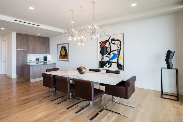 dining room with light hardwood / wood-style floors, a notable chandelier, and sink