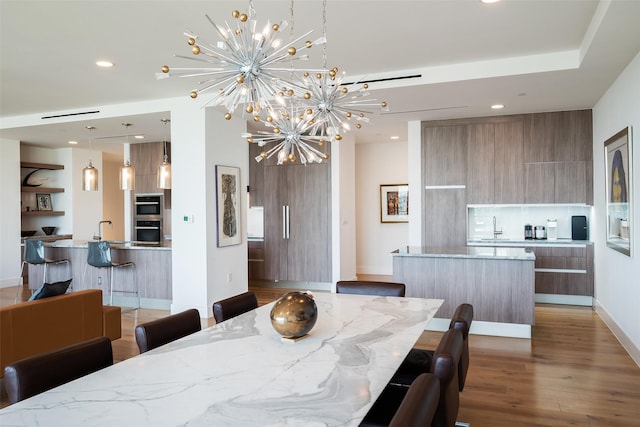 dining room featuring sink, hardwood / wood-style floors, and a notable chandelier