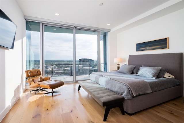 bedroom featuring light wood-type flooring, a wall of windows, and access to outside