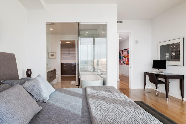 bedroom featuring ensuite bath, a walk in closet, a closet, and wood-type flooring