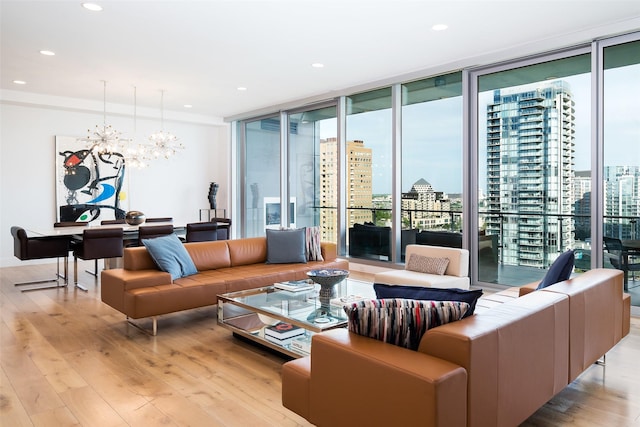 living room with plenty of natural light, an inviting chandelier, a wall of windows, and light hardwood / wood-style flooring