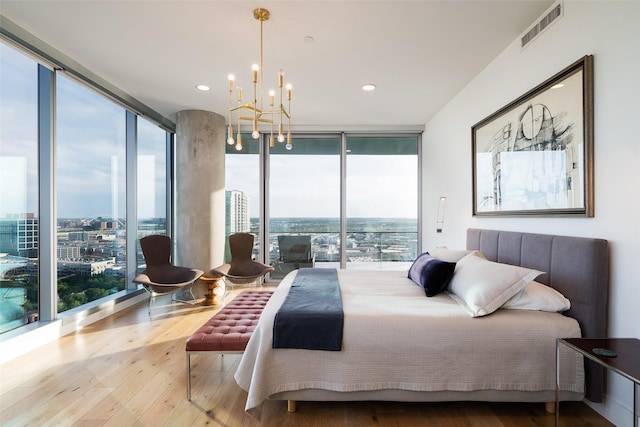 bedroom with hardwood / wood-style flooring, an inviting chandelier, and expansive windows