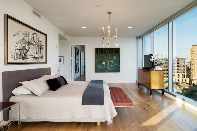 bedroom with hardwood / wood-style floors, a notable chandelier, access to exterior, and a wall of windows