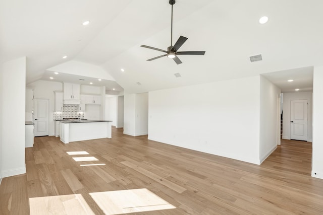 unfurnished living room with light hardwood / wood-style floors, ceiling fan, lofted ceiling, and sink