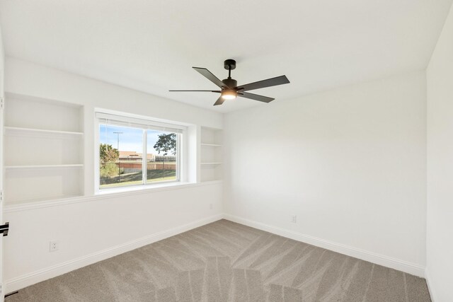 carpeted empty room featuring ceiling fan and built in features