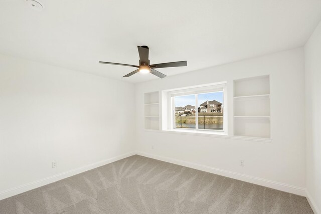 carpeted empty room with built in features and ceiling fan