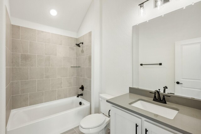 full bathroom featuring tile patterned flooring, lofted ceiling, toilet, vanity, and tiled shower / bath