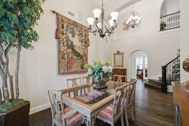 dining space featuring dark hardwood / wood-style flooring, a towering ceiling, and a notable chandelier