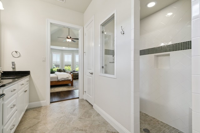 bathroom with tiled shower, vanity, and ceiling fan