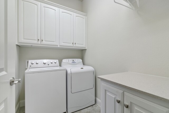 washroom with washer and clothes dryer, cabinets, and light tile patterned floors