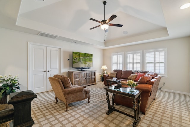 living room featuring ceiling fan and a tray ceiling