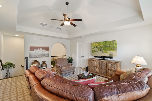 living room featuring ceiling fan, a raised ceiling, and light colored carpet