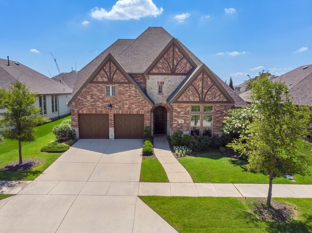 tudor-style house featuring a garage and a front lawn