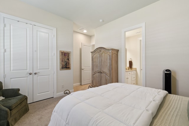 bedroom featuring light carpet, ensuite bathroom, and a closet