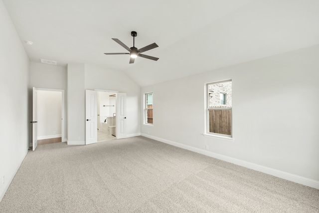 unfurnished bedroom featuring multiple windows, lofted ceiling, ensuite bath, and ceiling fan