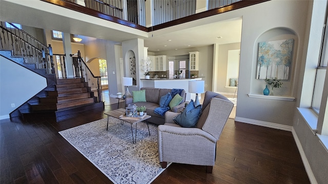 living room with dark hardwood / wood-style flooring and a towering ceiling