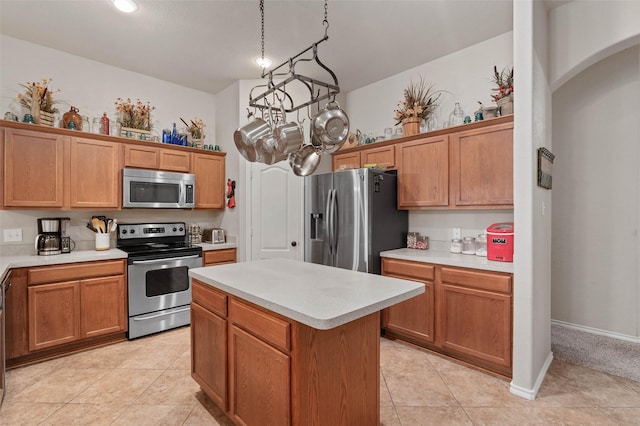 kitchen with decorative light fixtures, light tile patterned floors, stainless steel appliances, and a kitchen island