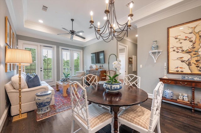 dining area with ceiling fan with notable chandelier, ornamental molding, dark hardwood / wood-style flooring, and a tray ceiling